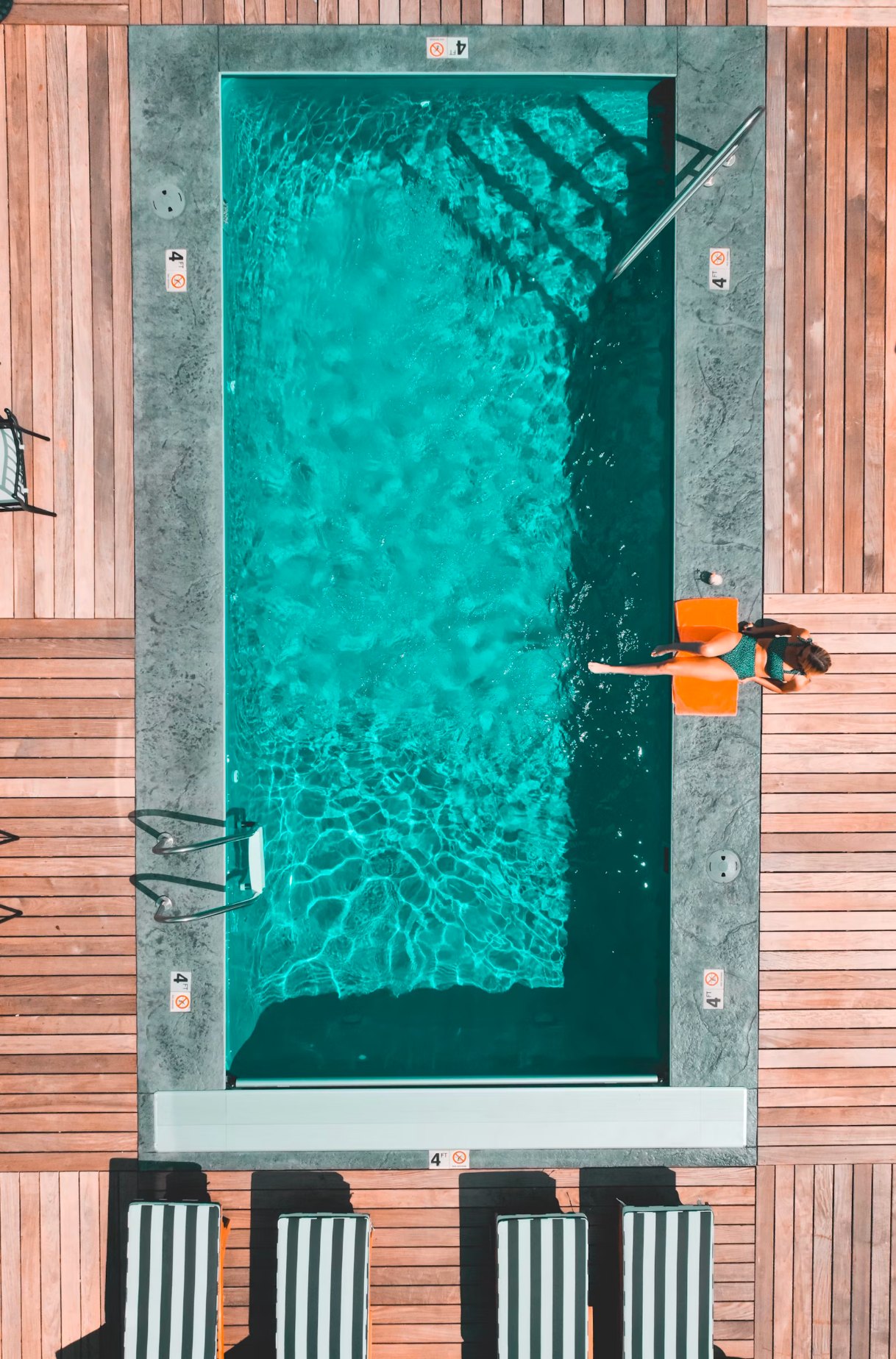 Piscina vista desde arriba con agua transparente y tarima de madera alrededor