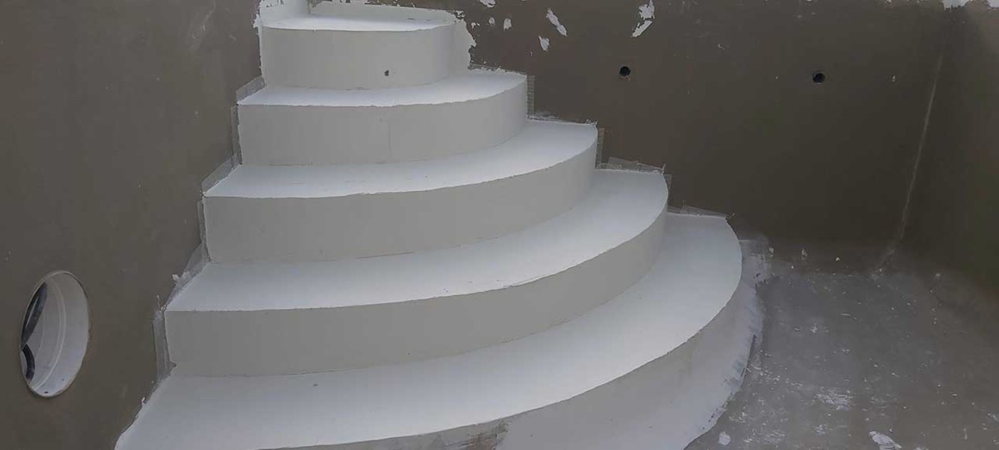 Escalera curva de obra dentro del vaso de una piscina, antes del revestimiento